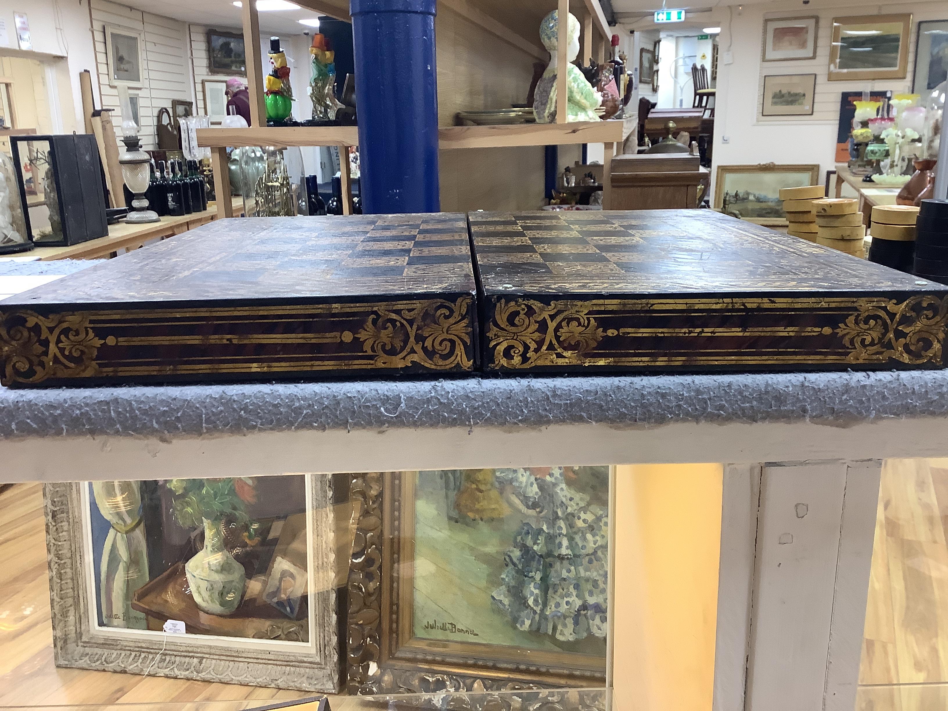 A 19th century papier maché folding games board for chess and backgammon, containing a wooden draughts set etc. with gilt decoration, 41 x 45cm unfolded